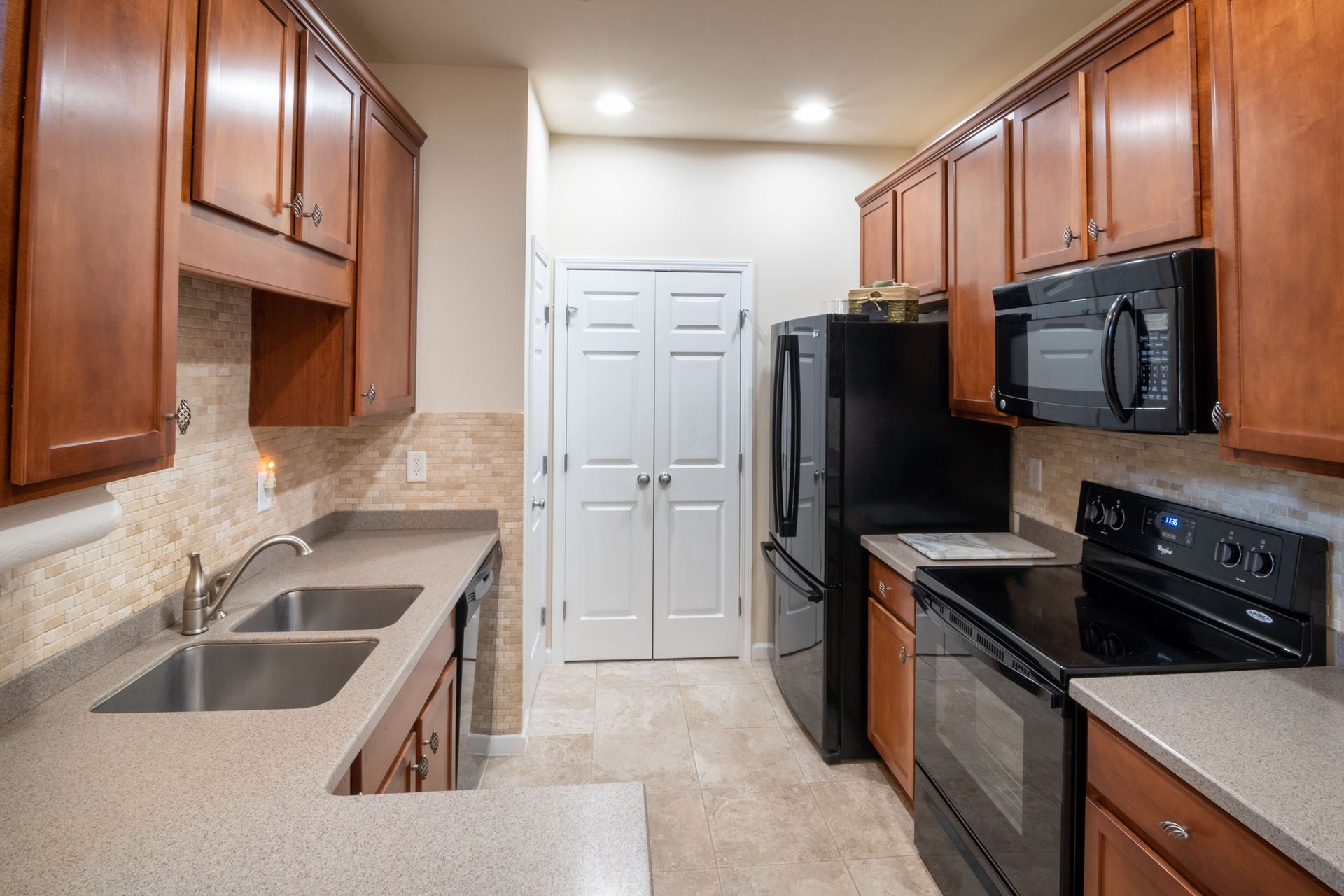 Spacious modern kitchen with wood cabinets, sleek countertops, and stainless steel appliances.
